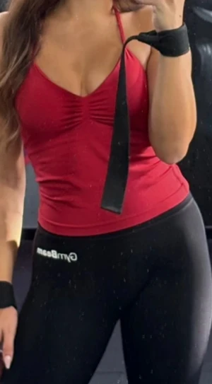 Röd gymtopp stretchig - Säljer en röd bandeau tubtopp med smala axelband och snygg rynkdetalj framtill. Toppen är figurnära och har en öppen rygg, perfekt för dig som gillar en enkel men stilren look. Materialet känns mjukt och stretchigt, troligen polyester eller bomull.