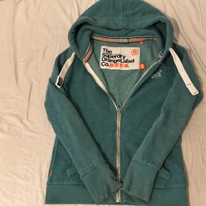 Superdry grön hoodie - Grön hoodie från superdry orange label. Snygg passform. Tveka inte på att skriva ifall du undrar nåt!