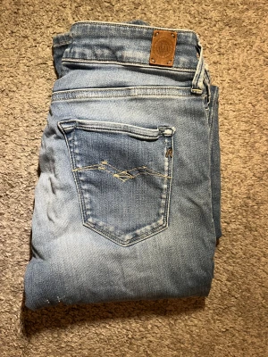 Replay ljusblå skinny jeans W27 L32 - Säljer ett par ljusblå skinny jeans från Replay med snygga slitningar och klassisk femficksdesign. W27 L32