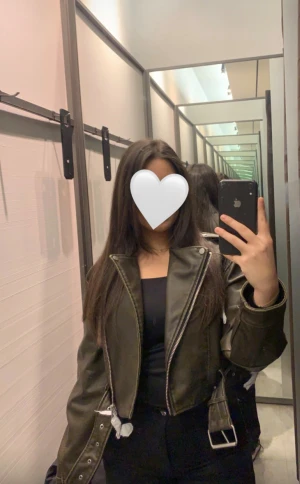 Svart croppad skinnjacka från Zara - Säljer en svart croppad skinnjacka från Zara med coola detaljer som bred krage, dragkedja och bälte i midjan. Jackan har lång ärm och en snygg, lite oversized passform som ger en edgy vibe. Perfekt att styla med jeans eller klänning.