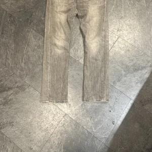 Polo grå jeans straight fit - Säljer ett par gråa polo  jeans med klassisk straight fit. Jeansen har fem fickor, snyggt slitna detaljer och Levi's patch bak i midjan. Materialet är robust denim i bomull och färgen är en ljusgrå ton med tvättad look.