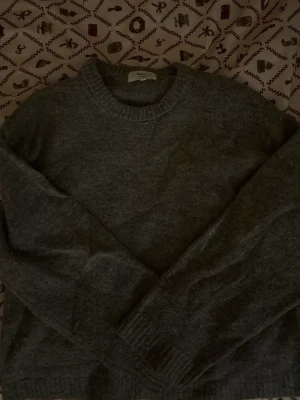 Grå stickad tröja från Gina Tricot💞 - Mysig grå stickad tröja från Gina Tricot i ullblandning. Tröjan har rund hals, ribbade muddar vid ärmslut och nederkant samt långärmad passform. Perfekt för kyliga dagar och enkel att matcha med jeans eller kjol.