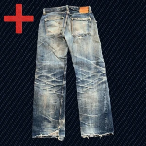 Vintage Archive Japanska Selvedge Jeans (The Flat Head) - Ett par vintage Japanska Selvedge Jeans från märket The Flat head! Storlek på taggen: 33 (se mått nedan!). Fint skick, har blivit lagade till stor del men finns några mindre olagade slitningar kvar som t.ex heelbite. Skriv om du har frågor!  Mått: Storlek på tag – 33, Midja – 40 cm, Lår – 30 cm, Innersöm – 77 cm, Längd – 102 cm, Benöppning – 23.5 cm