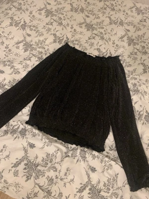 Glittrig tröja Kappahl - En svart glittrig tröja från Kappahl i storlek 158 men den passar storlek XS-S skulle jag säga för den är väldigt stretchig och lös i passformen. Materialet är jätte skönt och luftigt. En fin blush/tröja som passar bra om man vill klä upp sig!🩷