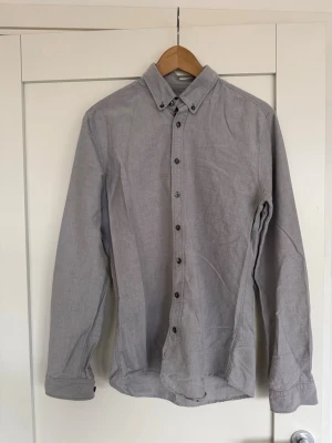 Grå skjorta från Tiger of Sweden - Slim fit skjorta i grått från Tiger of Sweden. Skjortan har klassisk krage med knappar och långa ärmar. Materialet är bomull och den har en stilren look med knappar hela vägen framtill.