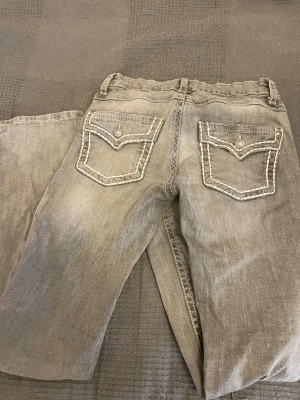 Grå bootcut jeans från Gina Tricot  - Snygga grå jeans med bootcut passform och coola kontrastsömmar. Baksidan har två fickor med lock och dekorativa knappar. Perfekt för dig som gillar en avslappnad men trendig look. Säljer därför att de är för små för mig❤️