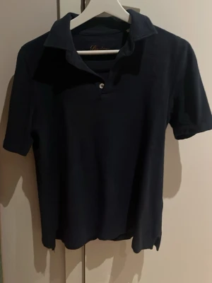Mörkblå frotté polotopp Stenströms S - Säljer en mörkblå polotopp från Stenströms i storlek S. Toppen är tillverkad i mjuk frotté och har korta ärmar, krage och knapp framtill. Diskret broderad logga på ärmen. Perfekt för dig som gillar klassisk och stilren design. Mitt pris 649kr