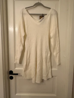 Vit ribbad stickad klänning Pieces - Superfin vit stickad klänning från Pieces i storlek L. Klänningen har ribbad struktur, lång ärm och snygg v-ringad hals. Helt ny och oanvänd 