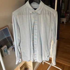 Ljusblå skjorta från Only & Sons - Snygg ljusblå skjorta från Only & Sons i slim fit. Skjortan har klassisk krage, långa ärmar och knäppning framtill. Perfekt för dig som gillar en stilren och enkel look. Tillverkad i mjukt bomullstyg som känns skönt mot huden.