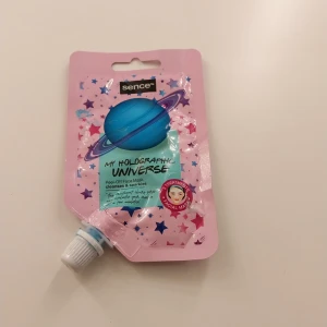 Sence My Holographic Universe ansiktsmask - Peel-off ansiktsmask från Sence i en rosa stjärnmönstrad förpackning med blått planetmotiv. Masken är holografisk och har en skimrande blå färg. Tuben rymmer 28 ml och har praktisk skruvkork. Perfekt för dig som gillar glittriga och roliga hudvårdsprodukter.