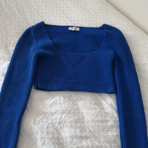 Blå croppad stickad topp Chiquelle - Säljer en blå croppad stickad topp från Chiquelle i storlek S. Toppen har lång ärm, fyrkantig halsringning och är ribbstickad för en snygg struktur. Perfekt att styla med höga jeans eller kjol för en trendig look.