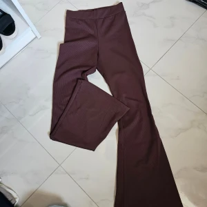 Bruna ribbade bootcut byxor S - Snygga bruna ribbade byxor från Light Women i storlek S. Byxorna har bootcut-modell med utsvängda ben och hög midja. Materialet är stretchigt och bekvämt, perfekt för en trendig och avslappnad look.