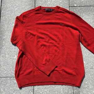 Röd merinoullströja från Morris XL - Snygg röd tröja från Morris i 100% merinoull. Klassisk rund halsringning och diskret broderad logga på bröstet. Perfekt för dig som gillar stilrena och bekväma plagg med en modern touch. Långärmad modell med ribbade muddar.