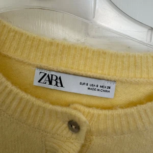 Gul kofta med volang från Zara - Supersöt ljusgul kofta från Zara med volangkant längs nederdelen och ärmsluten. 