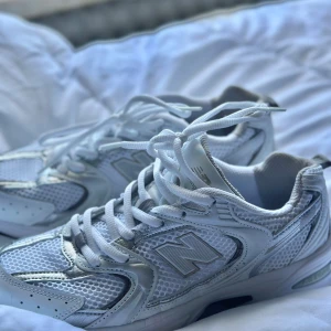Vita New Balance sneakers  - Säljer ett par fräscha vita New Balance sneakers med klassisk siluett. Skorna har meshpaneler och detaljer i syntet, samt snörning framtill. Perfekta för dig som gillar sportig och clean stil.