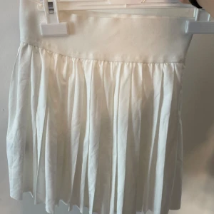 Vit plisserad kjol från SHEIN XXS - Superfin vit plisserad kjol från SHEIN i storlek XXS. Kjolen har bred linning och är kort med inbyggda shorts under för extra komfort. Perfekt för dig som gillar en clean och fräsch stil. Materialet är mjukt och lätt, vilket gör den skön att bära hela dagen. Inte använd. Tennis kjol