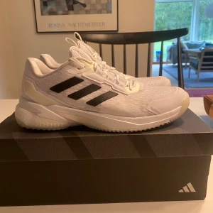 Vita Adidas sneakers med svarta ränder - Helt nya crazyflight 5 handbollskor. Vit sula och sko med svarta detaljer. Endast provad på handbollsplanen en gång. Kommer ej till användning pga skada. Original adidaskartong medföljer Storlek : 41 1/3. Motsvarar 26cm i fotlängd. Nypris: 1649kr