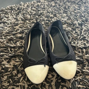 Svarta ballerinaskor med vit tå - Snygga ballerinaskor från H&M i svart tyg med vit tå och liten rosett framtill. Säljer pga dom ej kommer till användning🤍