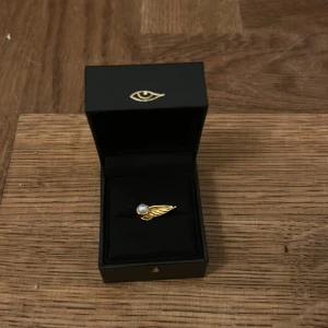 Örhänge Maria nilsdotter - Supersnyggt örhänge från Maria Nilsdotter som ska föreställa en vinge med en pärla i. Inte använt alls utan bara typ 2 gånger men älskar den mest asså!!