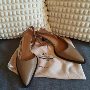 Beige pumps/slingback från ATP Atelier, skinn - Snygga beige pumps från ATP Atelier i äkta nappaskinn. Desana slingbacks har spetsig tå, låg klack 5.5cm och öppen häl med smal rem. Tillverkade i Italien och har en stilren, minimalistisk design som passar perfekt till många outfits.