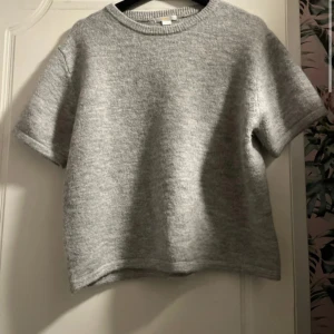 Grå stickad kortärmad tröja - En enkel och stilren grå stickad tröja med korta ärmar och rund hals. Perfekt för dig som gillar en clean look och vill ha något mjukt och bekvämt. Passar till jeans eller kjol och är lätt att matcha med. Använd typ 3 gånger och är i storlek 170!!💕