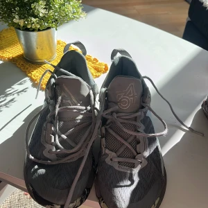 Giannis immortality 2 - Säljer ett par grå Nike sneakers med coolt 34-märke på plösen och vit swoosh på sidan. Skorna har snörning, mesh- och syntetmaterial samt en unik svartvit mönstrad sula. Perfekta för dig som gillar basket och vill sticka ut lite extra på planen.