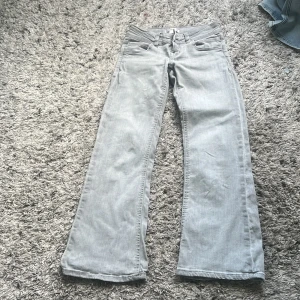 Gråa wide jeans från Gina Tricot - Snygga ljusgrå jeans från Gina Tricot i storlek 140. Modellen har raka, vida ben. Jeansen har dragkedja och dubbla silverfärgade knappar i midjan. Perfekta för en cool och avslappnad look. Säljer pga försmå.
