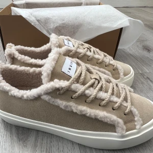 Beige sneakers från Inuikii - Säljer ett par snygga beige sneakers från Inuikii. Skorna har snörning, platt vit sula och är gjorda i mocka. Perfekta för dig som vill ha både stil och komfort under kyligare dagar. 💕