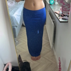 Blå långkjol i stretchigt tyg - Säljer en enkel och snygg blå långkjol i stretchigt material. Kjolen har en tight passform och sitter högt i midjan. Perfekt för dig som gillar en stilren look med lite edge. Färgen är klarblå och tyget är mjukt och följsamt.