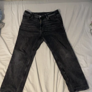 Svarta raka jeans i storlek 164 - Säljer ett par svarta jeans med raka ben och klassisk femficksdesign. Jeansen har en mörk tvätt och är tillverkade i jeansmaterial. Passar dig som gillar en enkel och stilren look.
