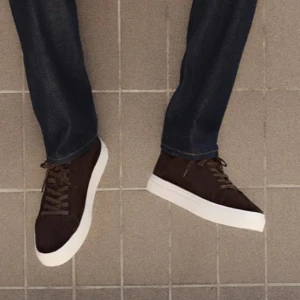 Bruna vagabond mockasneakers med vit sula - Snygga sneakers i mörkbrun mocka med klassisk rund tå och platt vit sula. Skorna har bruna snören och en stilren design som passar till jeans eller chinos. Perfekta för dig som gillar en clean och tidlös look. Aldrig använda i storlek 42, 271-277 mm.