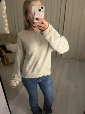 Beige stickad tröja från LMTD - Mysig beige stickad tröja från LMTD i storlek S. Tröjan har en avslappnad passform med långa ärmar och ribbade muddar vid hals, ärmslut och nederkant. Perfekt för lager-på-lager under kyliga dagar.