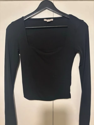 Svart långärmad topp  - En svart, långärmad topp  Toppen är enkel och stilren, perfekt att matcha med olika outfits. 