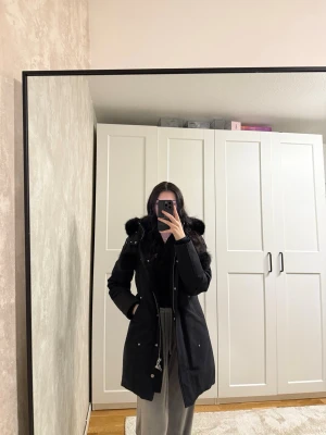 Vinterjacka moose knuckles  - Säljer en svart från Moose Knuckles med fluffig pälskant på huvan och detaljer i silver. Jackan har dragkedja, knappar och två stora fickor framtill. Klassisk logga på ärmen och snygga pälspuffar på snörena. Perfekt för kalla dagar.   Jackan är använd endast en vinter och har inte defekter. Jag är själv en storlek xs/s och jackan är M men passar fortfarande perfekt