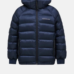 Mörkblå Peak Performance dunjacka - Säljer denna snygga mörkblå dunjacka från Peak Performance med huva och dragkedja framtill. Jackan har quiltad design, ribbade muddar och två sidofickor med dragkedja. Perfekt för kalla dagar!🥰och nu till skidsäsongen. Skriv om ni vill ha bilder!