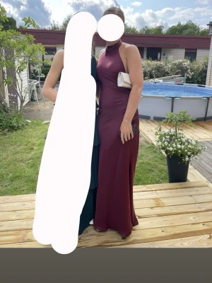 Vinröd balklänning med öppen rygg - Fin balklänning i vinrött silkigt material med hög hals och öppen rygg, knytning i nacken. Köpt från boohoo, använd endast vid två tillfällen. 