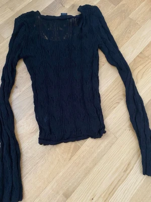 Svart stickad tröja från Lindex XS - Säljer en svart, tunnstickad tröja från Lindex i storlek XS. Tröjan har lång ärm, rund halsringning och ett genombrutet mönster som ger en cool och luftig känsla. Perfekt att styla lager på lager eller med ett linne under.