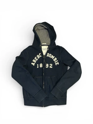 Vintage Abercrombie and Fitch Zip Hoodie - Säljer en riktigt snygg Vintage Abercrombie and Fitch Zip Hoodie storlek L men kan passa M även. Finns tecken på användning men bra skick i överlag. Färg mörkblå   Skriv vid vidare funderingar!