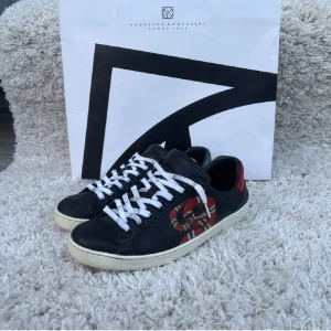 Gucci sneakers med orm mönster - Snygga svarta sneakers från Gucci med vit sula, vita snören och ikoniskt GG-mönster. Skorna är i bra skick och i storlek 42 inget og kommer med tyvärr skorna är väldigt unika!🤩🤩🤩tar ej imot returer