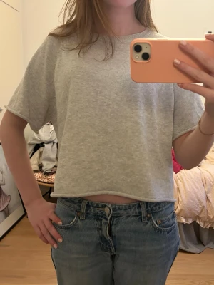 Ljusgrå virkad t-shirt - En enkel och stilren ljusgrå croppad virkad t-shirt med rund halsringning och korta ärmar. Perfekt till jeans eller kjol för en avslappnad look. Mjuk och skön mot huden. Storlek M men passar också S🩷