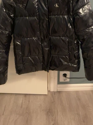 Svart pufferjacka från Calvin Klein Jeans - Säljer nu en svart glansig Calvin Klein Jeans jacka i storlek M men sitter som S.