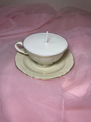 Doftljus i en tekopp i en vit färg nr 2 - Det här ljuset är gjort av återanvändbara material. Tekoppen är köpt secondhand och stearinet är från kyrkor som tänkte slänga det. Det här ljuset har en svag doft utav vanilj, så känsliga även kan använda det. Det finns även fler ljus med denna design på hemsidan, om man vill köpa sets. 
