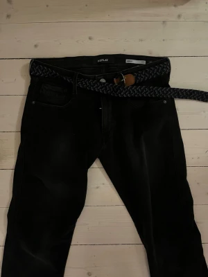 Svarta Replay Anbass slim jeans - Svarta Replay Anbass jeans i slim fit med klassisk femficksdesign. Snyggt smal passform som sitter tajt längs benen. Materialet är jeans och färgen är djup svart. Bälte medföljer ej. Perfekta för dig som gillar stilrena och moderna jeans.