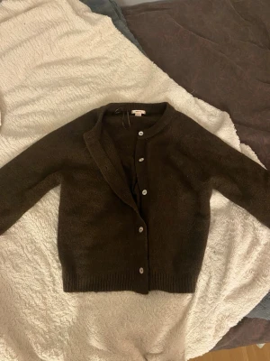 Mörkbrun kofta från Gina Tricot - Mysig mörkbrun kofta från Gina Tricot i storlek M. Koftan är stickad med långa ärmar, ribbade muddar och knäpps med vita knappar framtill. Jättefint skick, passar S, finns ej att köpa online, nypris 349😇