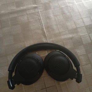 JBL trådlösa 720bt over-ear hörlurar - Snygga svarta JBL over-ear 720bt hörlurar med trådlös anslutning. Mjuka öronkuddar och justerbar bygel för bekväm användning. Inbyggda knappar för enkel kontroll. Hörlurarna ser ut att vara i gott skick utan synligt slitage eller defekter. 400kr