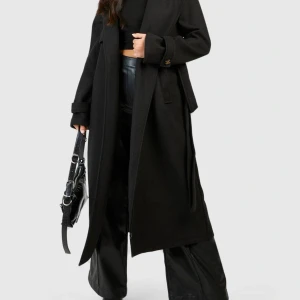 Kappa stillren   - Boohoo Petite Beldad trenchcoat med ull-look, strl 38 – svart. Elegant kappa i mjuk ull-look med avtagbart skärp och dubbelknäppning. Smickrande petite-passform som markerar midjan och passar perfekt till höst och vinter. I mycket fint skick!
