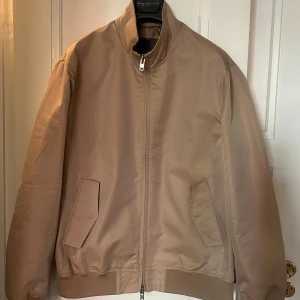 Brixtol Textiles Jacka - Beige harringtonjacka/baracuta med dragkedja framtill och ribbstickade muddar. Jackan har två fickor fram och en innerficka. Jättefint skick, knappt använd.  Storlek: L