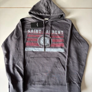 Saint Laurent Hoodie - Säljer en helt ny Saint Laurent hoodie, Aldirg andvänd. Står storlek M men sitter mycket mer Som S. Så rekommenderar att köpa om du normalt har storlek S. Priset är ej hugget är Sten.
