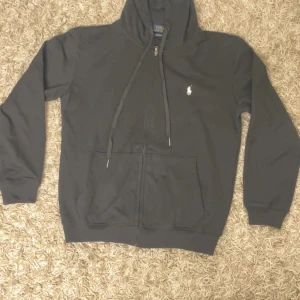Svart hoodie från Polo Ralph Lauren - Svart hoodie från Polo Ralph Lauren, använd några få gånger så är nästan helt ny, passar dig med storlek S, skriv om du har några andra frågor eller vill ha fler bilder!