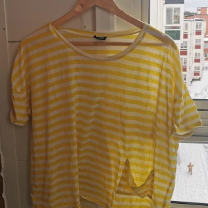 Gulvit randig t-shirt från JC - Snygg t-shirt från JC i gult och vitt med horisontella ränder. Modellen är loose fit med korta ärmar och rund halsringning. Den har en ficka som syns på bilden, väl använd men inte hittat några skavanker. Säljer för att jag inte längre använder den